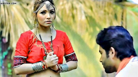 Sexy Indian woman in red embroidered blouse with bangles stares intensely at man