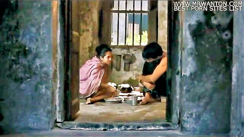 Sexy Indian woman in pink sari sits with shirtless man eating meal on prison cell floor