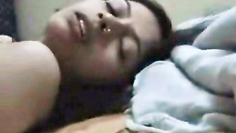 Indian woman lying relaxed in bed, eyes closed, implied nude under sheet