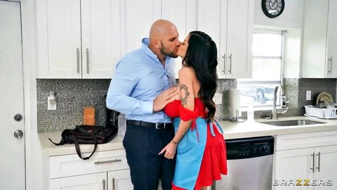 Muscular bald stud passionately kisses busty tattooed brunette in sexy apron dress in kitchen