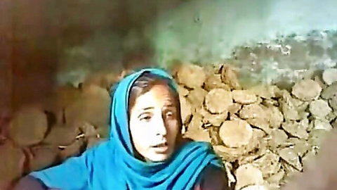 Shocked South Asian woman in blue hijab with open mouth amid cow dung piles in amateur outdoor scene