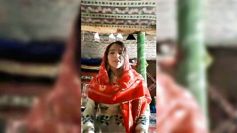 Beautiful Afghan girl in red traditional scarf and embroidered top at home