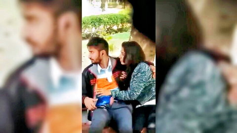 Sexy South Asian Indian couple cuddling intimately outdoors on park bench