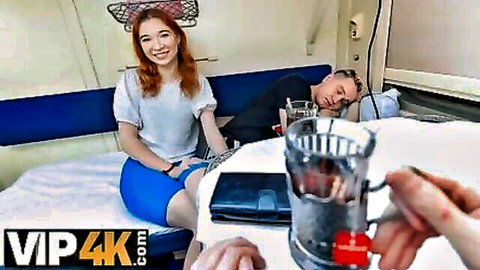 Smiling redhead babe in white blouse and skirt flirts in train compartment with sleeping man nearby POV