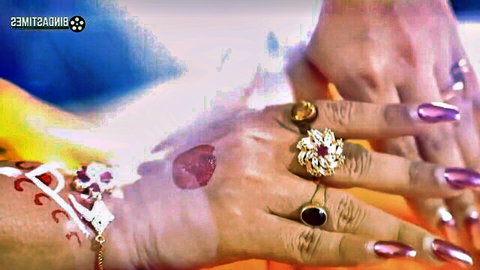 Close-up of sexy Indian woman's hands with intricate mehndi henna, gold rings, bracelets and long purple nails
