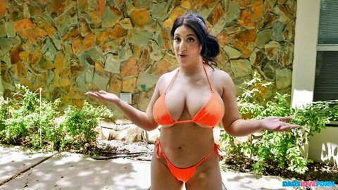 Curvy Arab brunette with huge tits in tiny orange bikini shrugs playfully outdoors