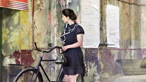 Elegant Asian woman in short black ruffled dress with bicycle