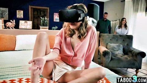 Young blonde in VR headset spreads legs teasing in open pink cardigan while man and woman voyeur from door